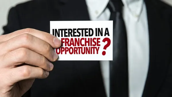Man holding interested in a Franchise Opportunity card.