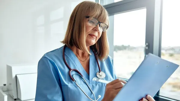 In a well-organized clinic, a skilled nurse reviews essential patient information, ensuring exceptional care and accurate documentation of medical procedures and vital findings crucial for health.